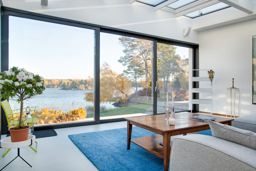 Modern aluminium bifold doors opening onto a blue lake view