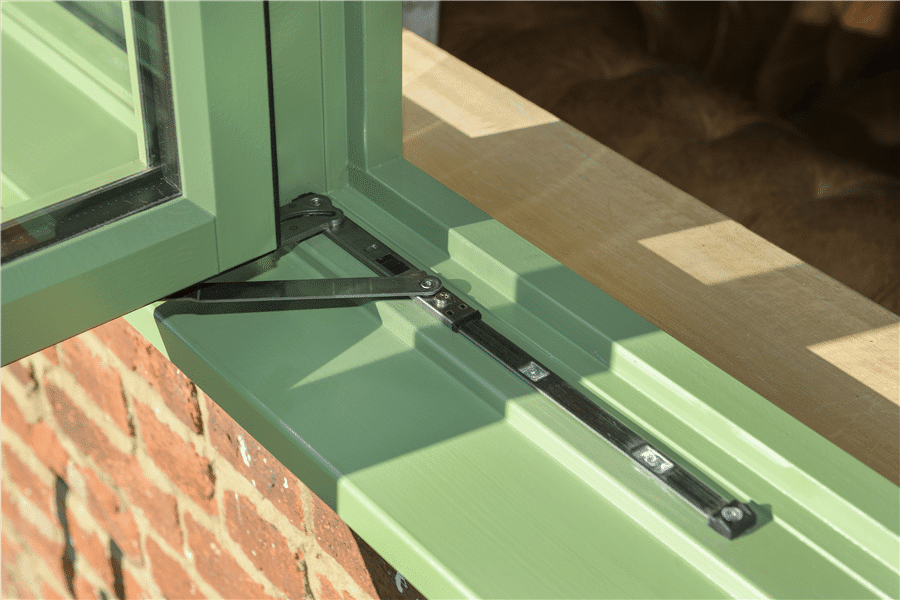 Sage green uPVC casement window exterior close-up—bottom-left frame and sill detail